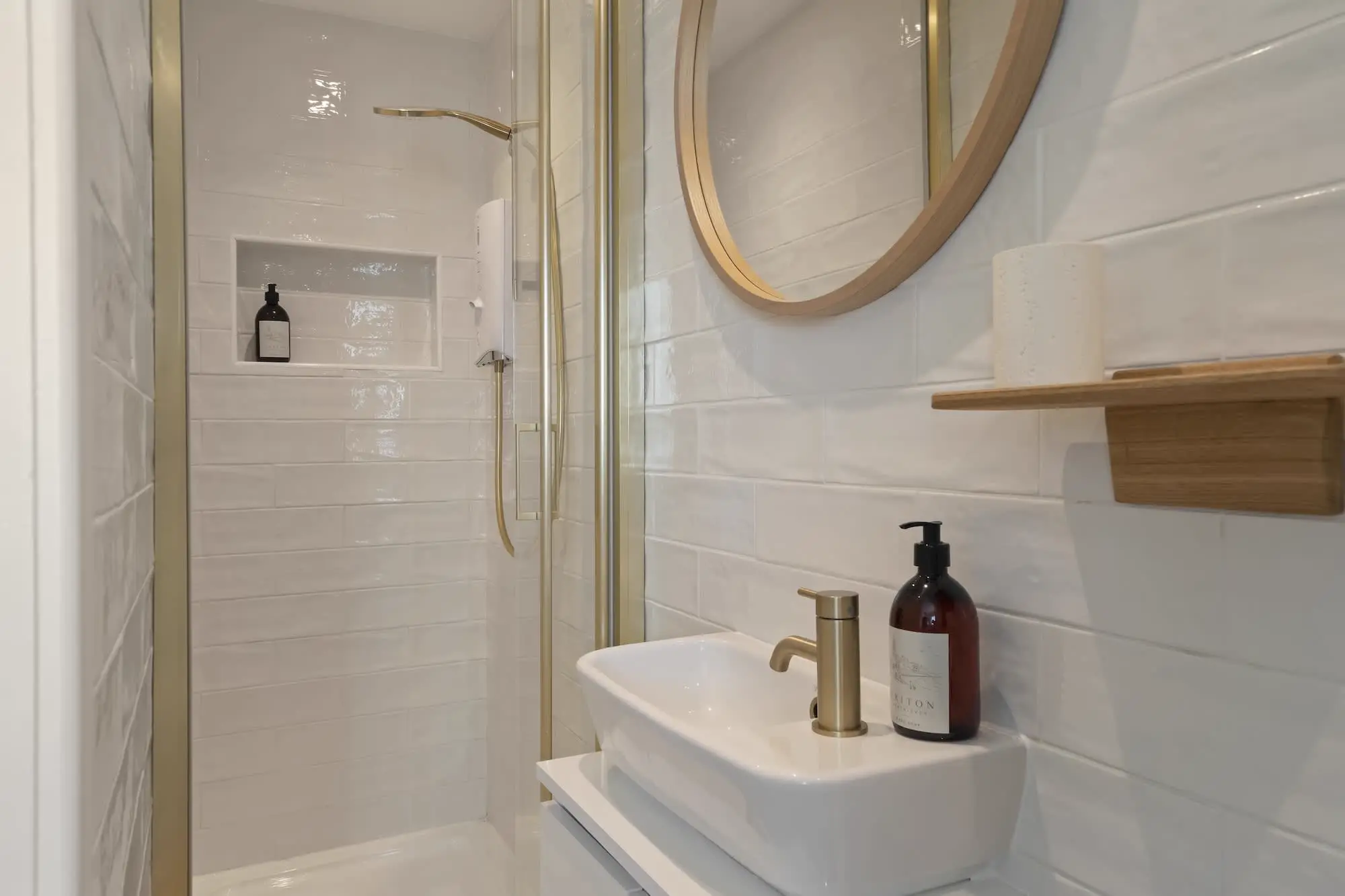 Shower room at Triton with walk-in shower, brass fittings and round mirror