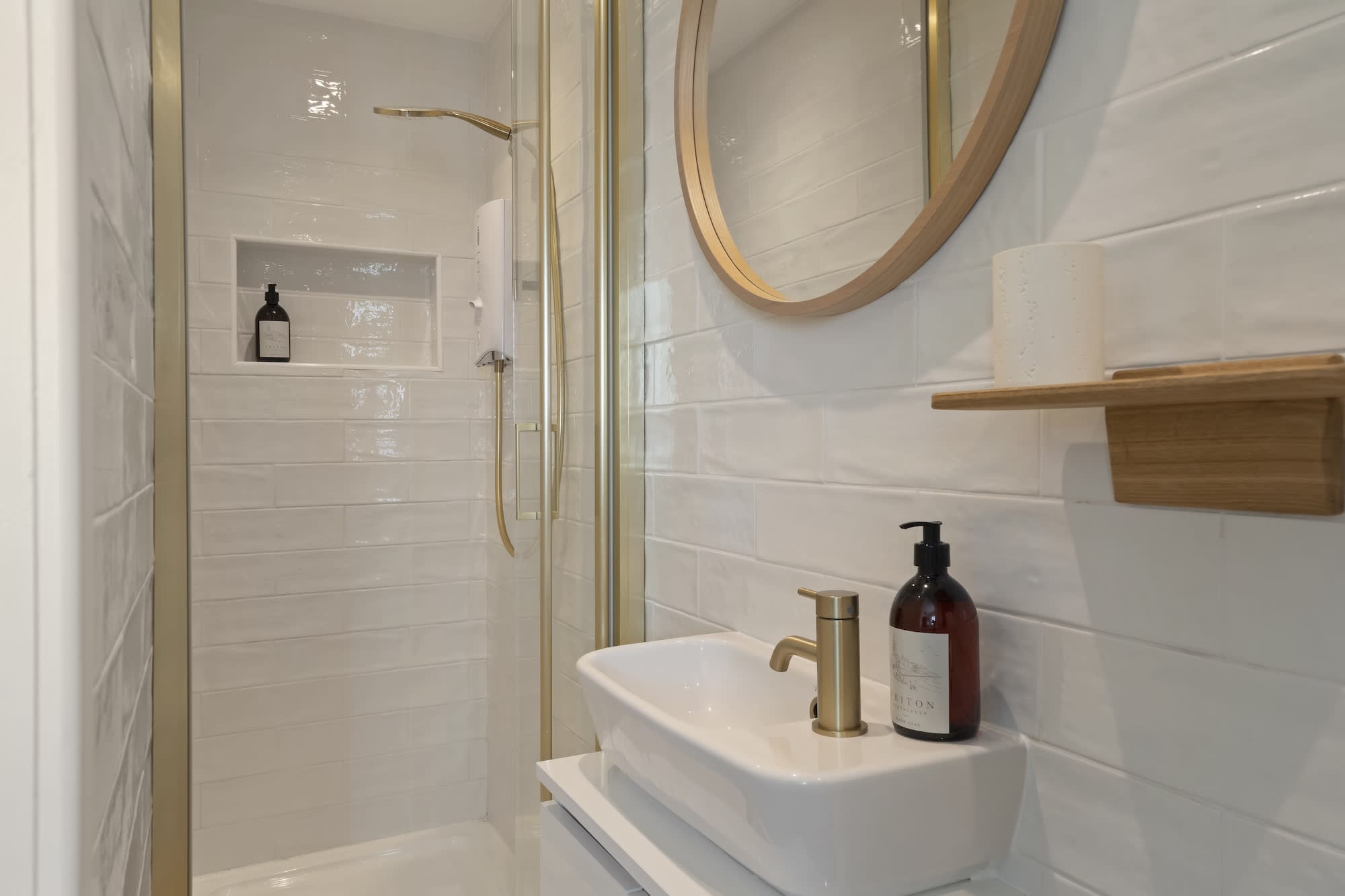 Walk-in shower room with brass fittings and round mirror