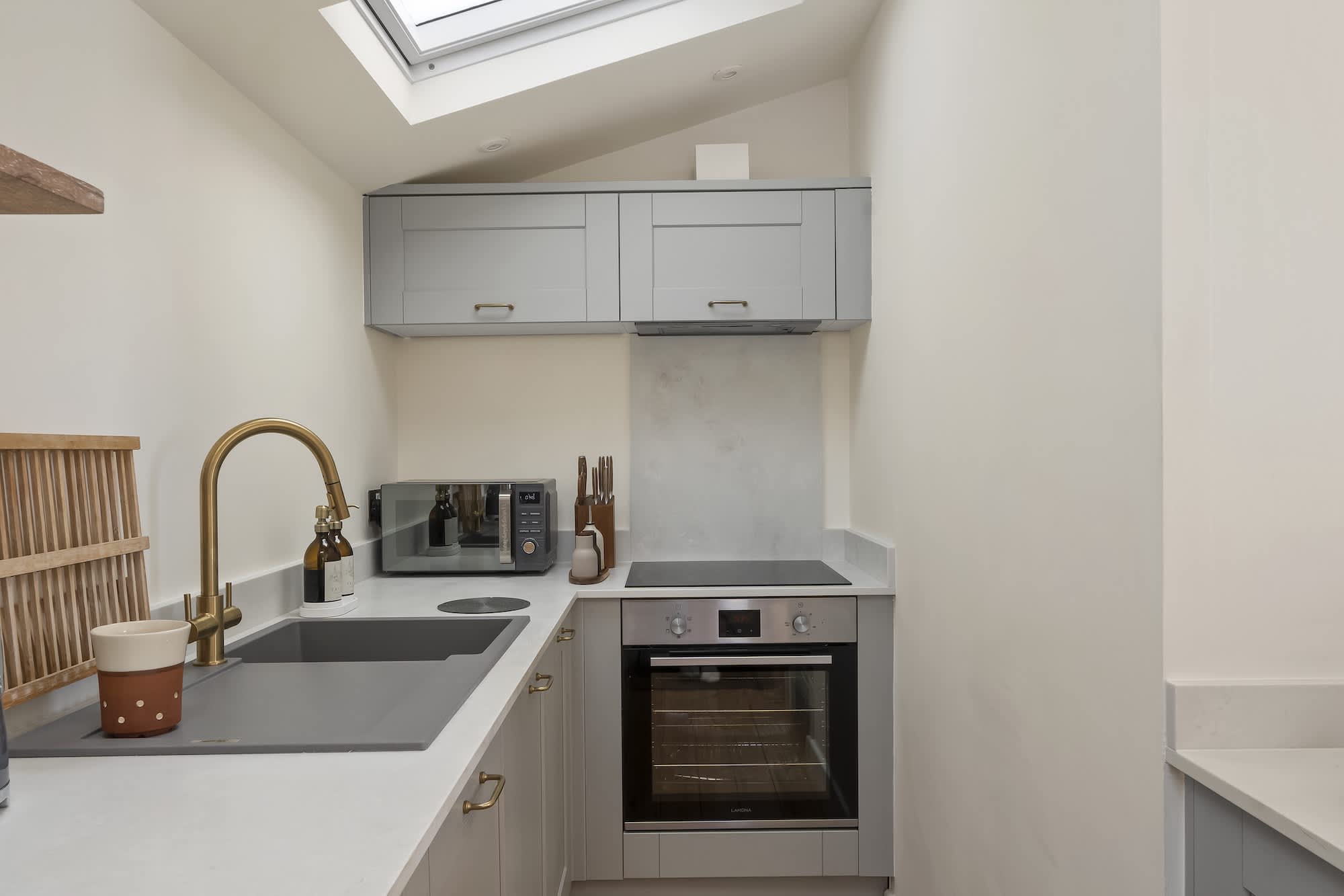 Compact shaker kitchen with brass tap under the skylight at Triton